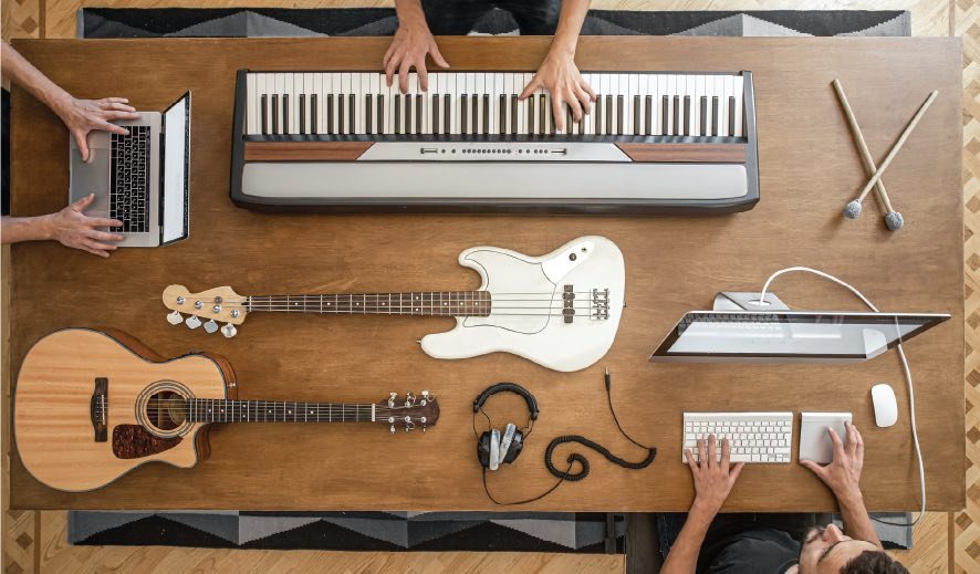 Guitar, bass guitar, piano, drum sticks, laptop, on table