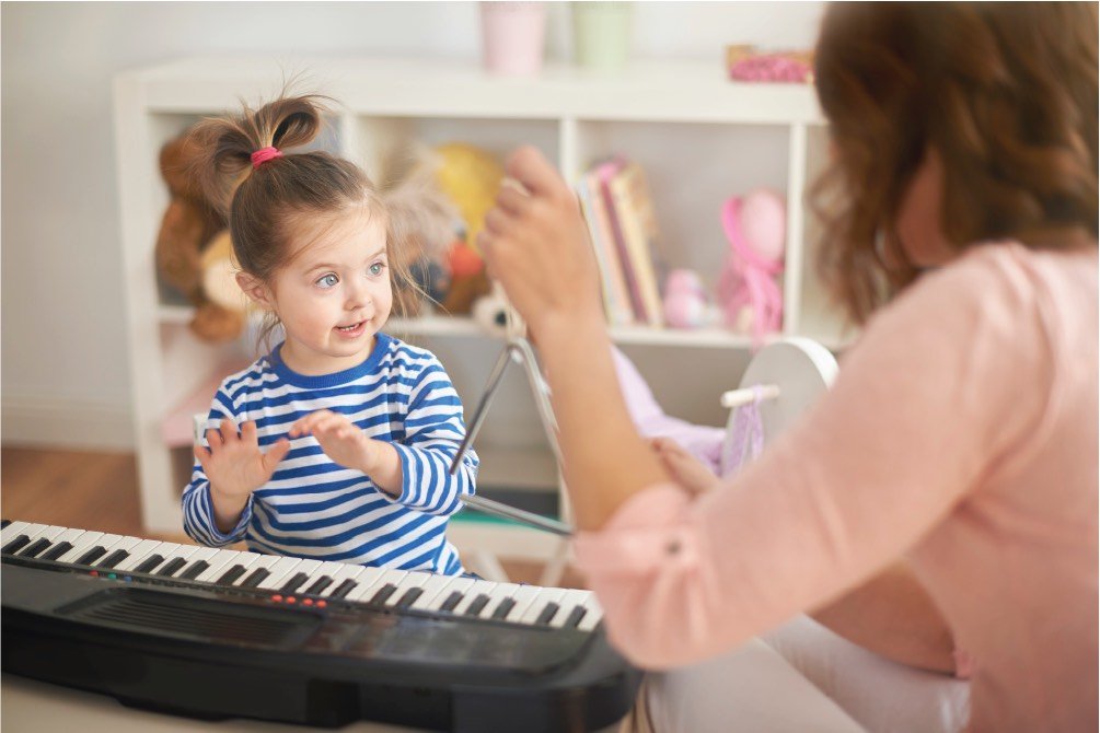 music teacher with girl playing piano